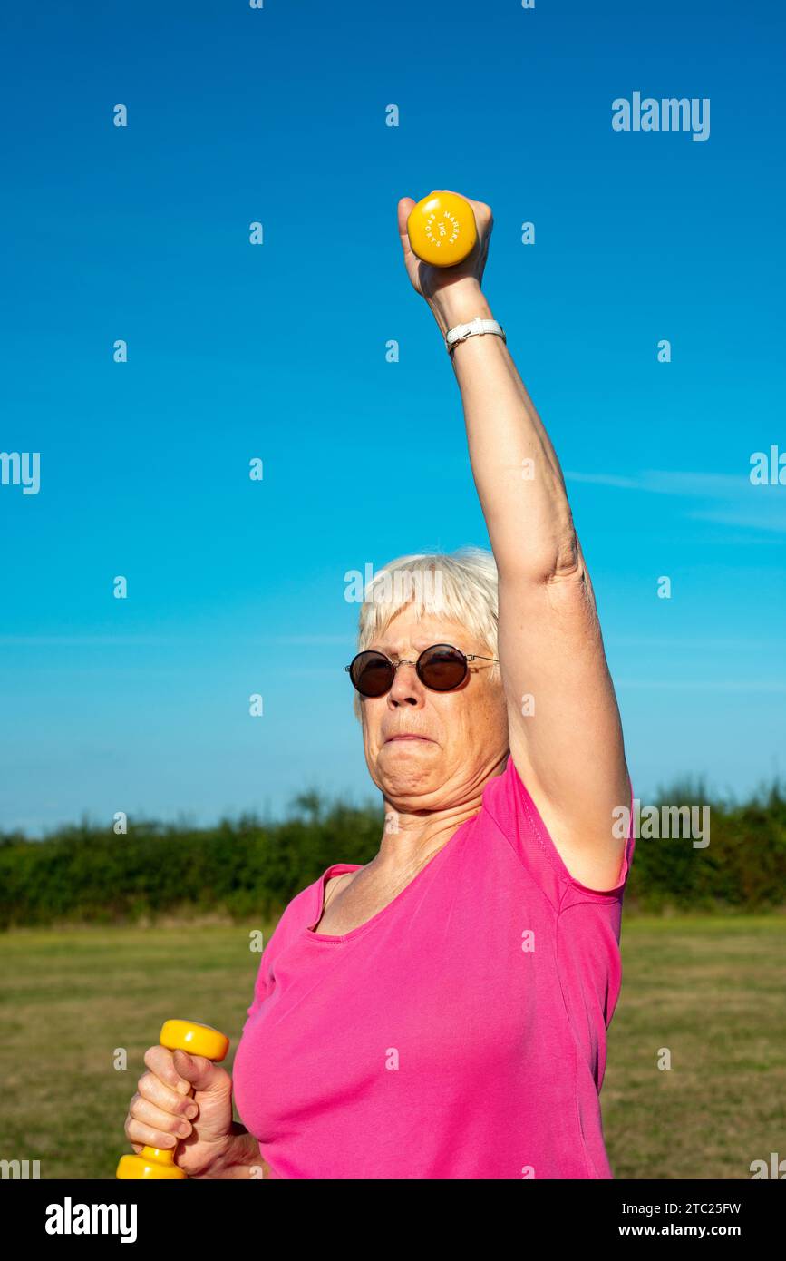 Donna anziana che usa pesi manubri per tenersi in forma Foto Stock