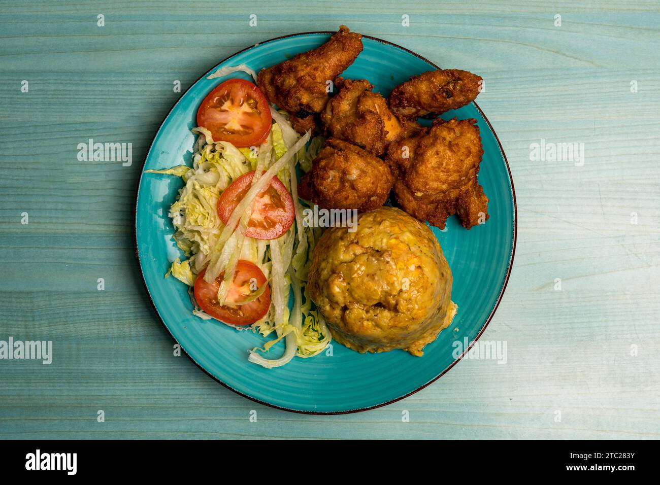 Ali di pollo fritte con purè di plantains e insalata Foto Stock