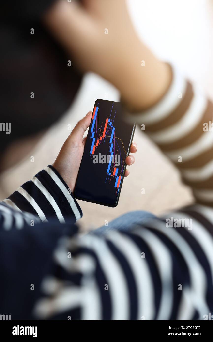 Concetto di investimento nel mercato azionario e nel mercato delle criptovalute. una donna sta controllando utilizzando le azioni dello smartphone sono crollate. Foto Stock