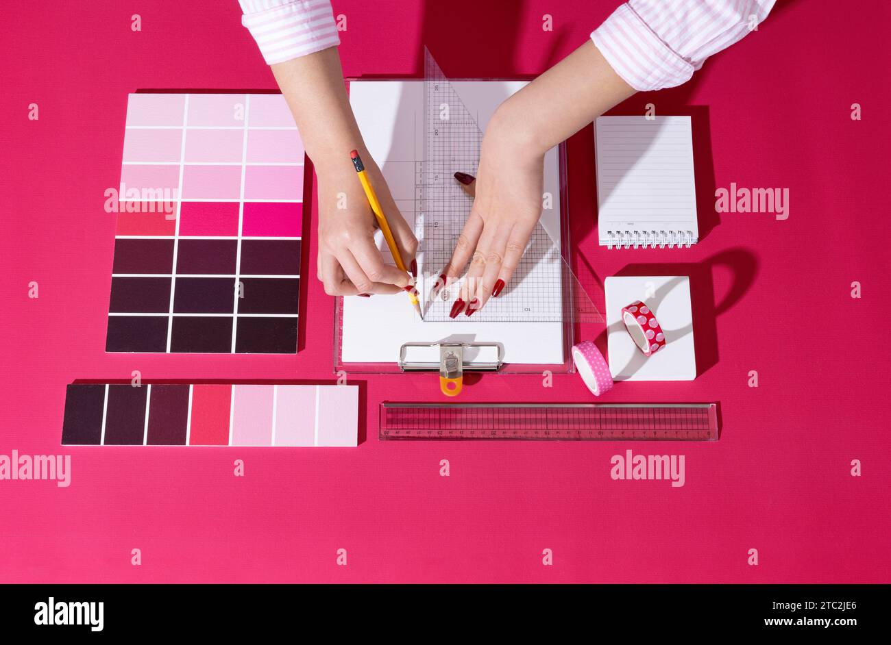 Un designer professionista che progetta con sfondi e oggetti di scena nel colore Viva Magenta Foto Stock