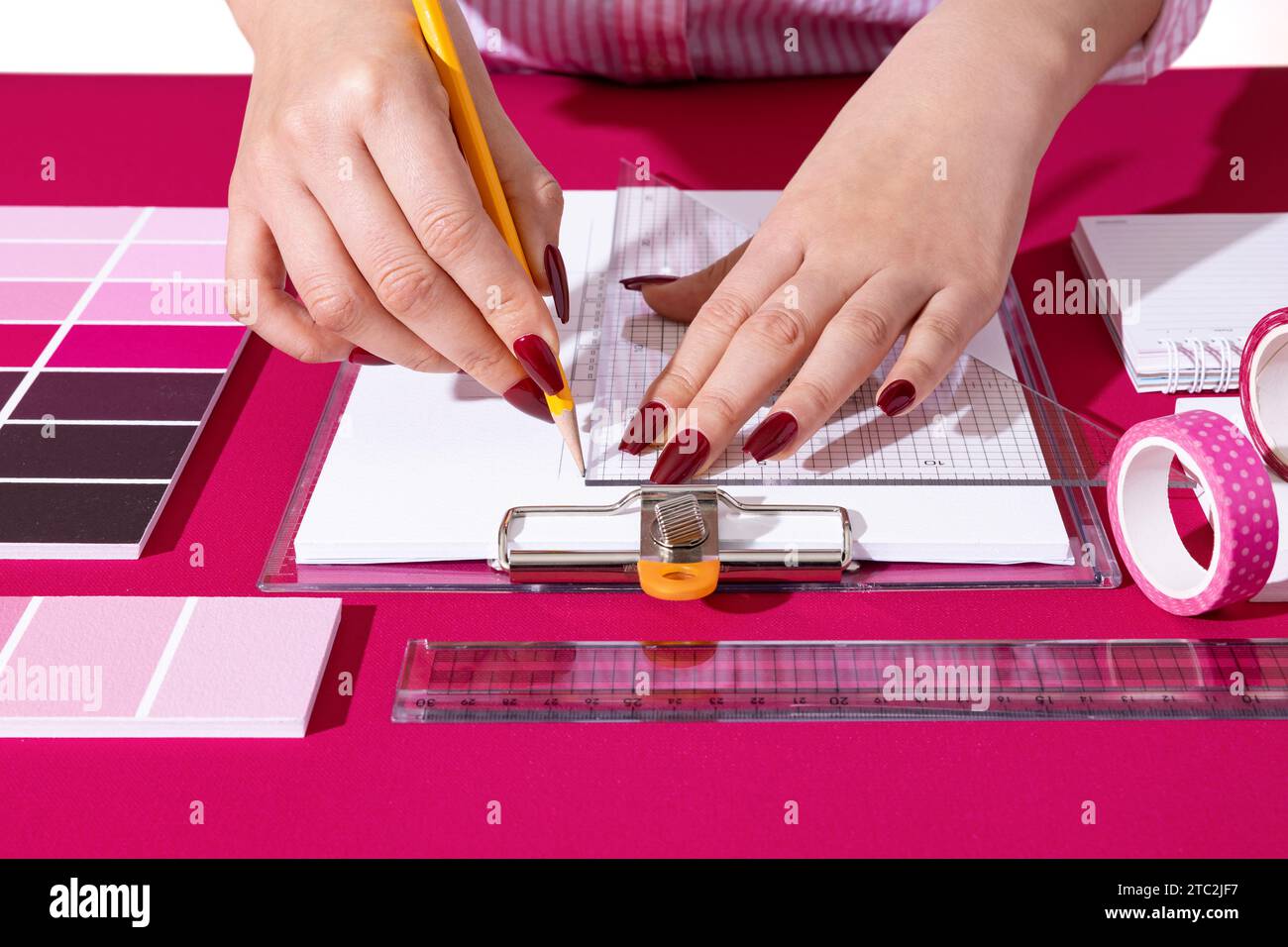 Un designer professionista che progetta con sfondi e oggetti di scena nel colore Viva Magenta Foto Stock