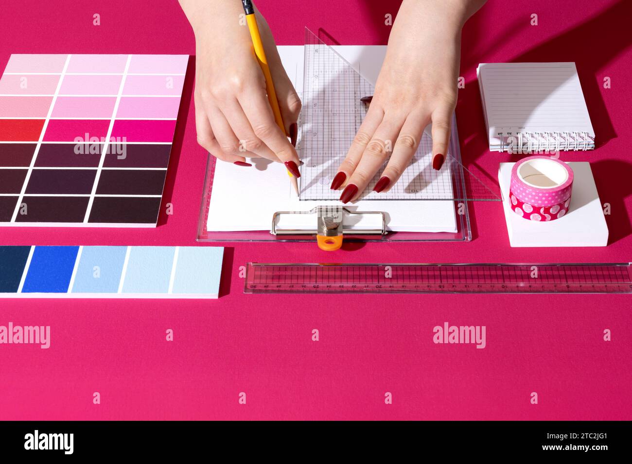 Un designer professionista che progetta con sfondi e oggetti di scena nel colore Viva Magenta Foto Stock