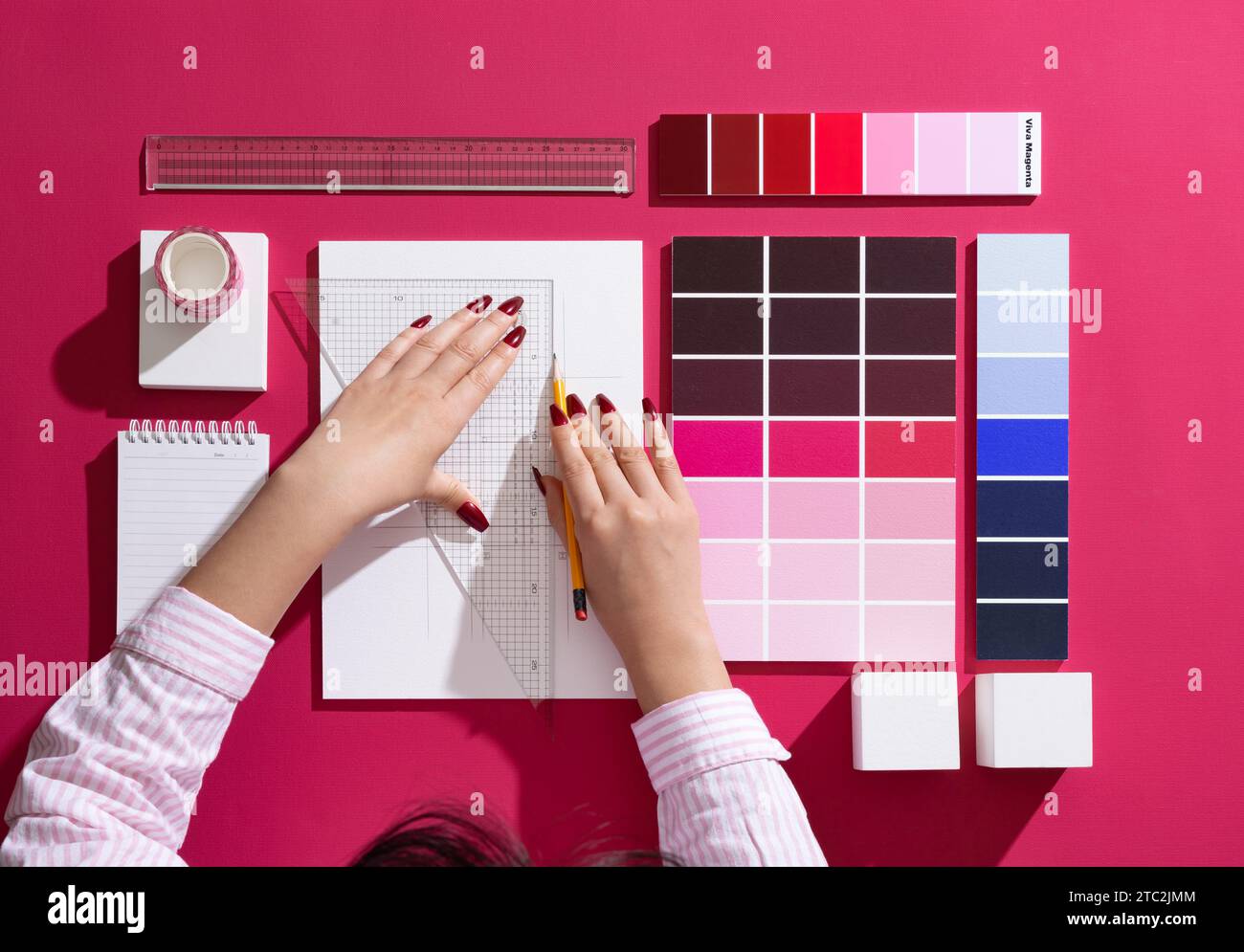 Un designer professionista che progetta con sfondi e oggetti di scena nel colore Viva Magenta Foto Stock