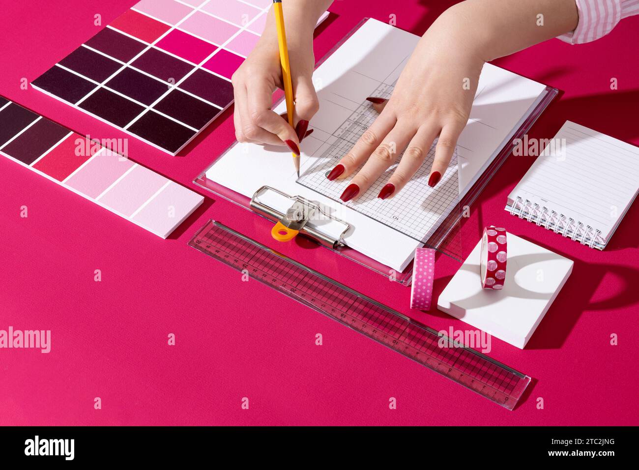 Un designer professionista che progetta con sfondi e oggetti di scena nel colore Viva Magenta Foto Stock