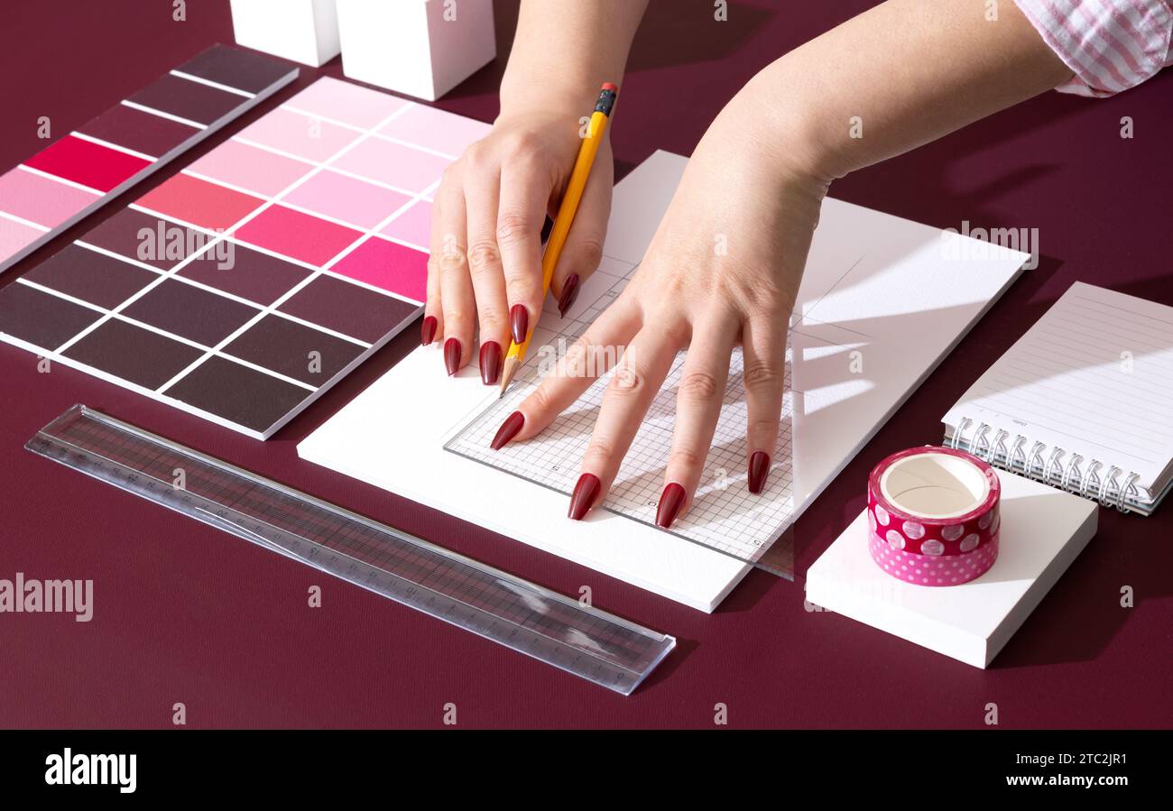 Un designer professionista che progetta con sfondi e oggetti di scena nel colore Viva Magenta Foto Stock