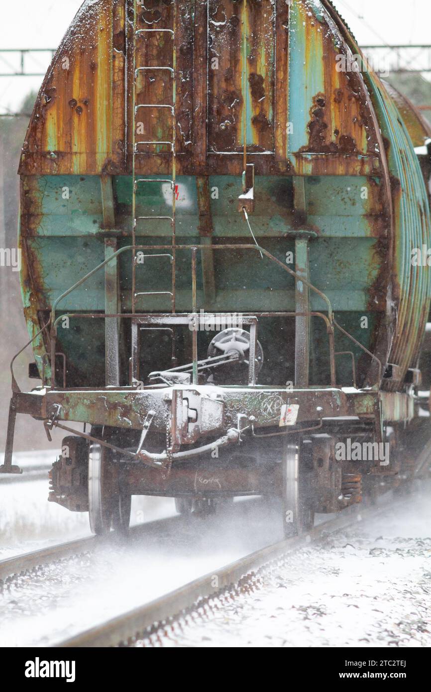 l'ultima vettura del treno merci parte per ferrovia attraverso una nevicata Foto Stock