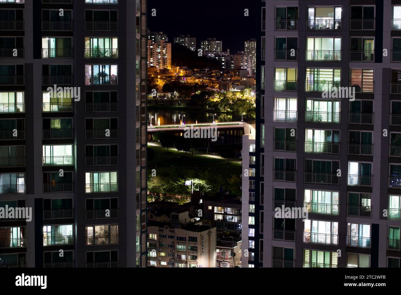 Lo skyline di Ulsan brilla sotto il cielo notturno, mostrando appartamenti illuminati e superfici riflettenti su uno sfondo illuminato da stelle. Foto Stock
