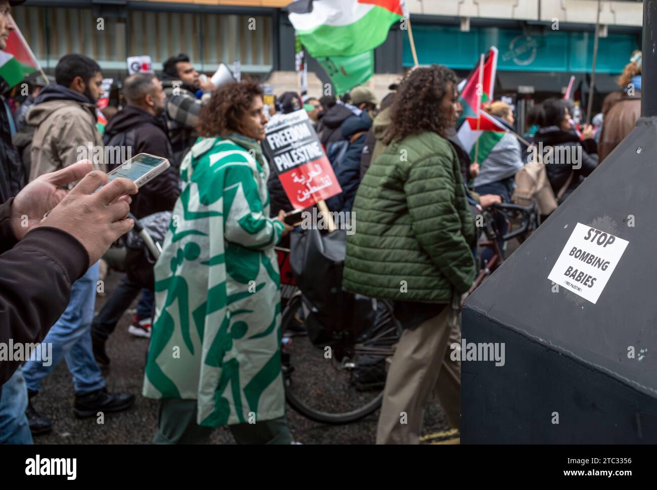 Londra / Regno Unito - 9 dicembre 2023: I manifestanti pro-palestinesi marciano davanti a un adesivo con la scritta "Stop Bombing Babies" durante una manifestazione che chiede la fine di Israele Foto Stock