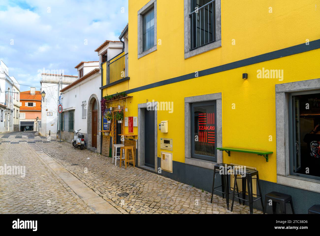 Un piccolo caffè marciapiede dipinto di giallo luminoso con sgabelli nel centro storico della località balneare di Cascais, Portogallo. Foto Stock