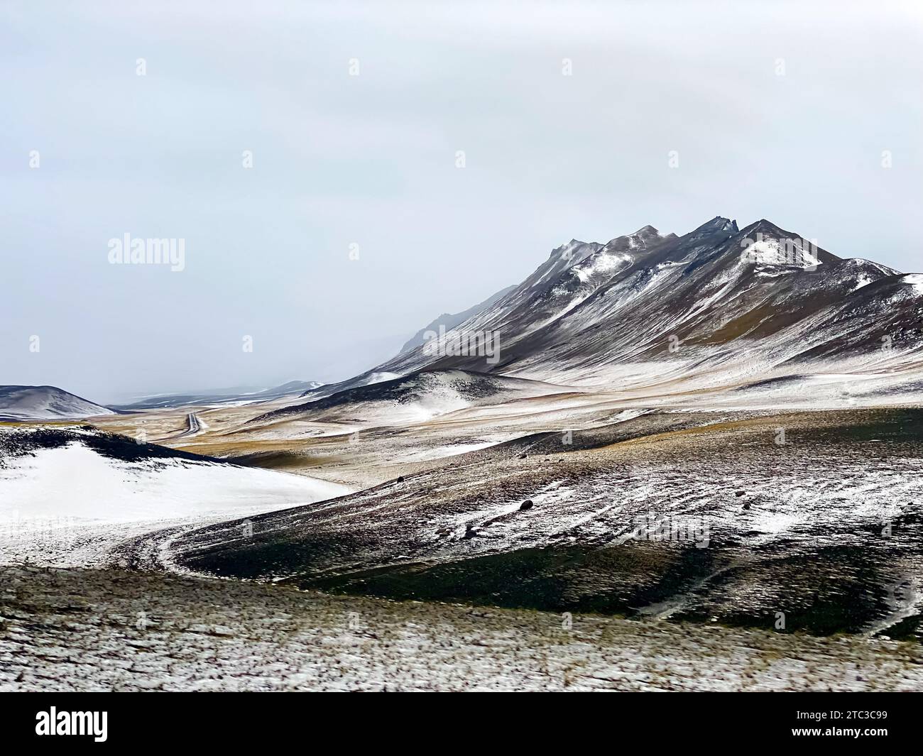 Strada tortuosa attraverso gli altopiani spolverati di neve dell'Islanda Foto Stock