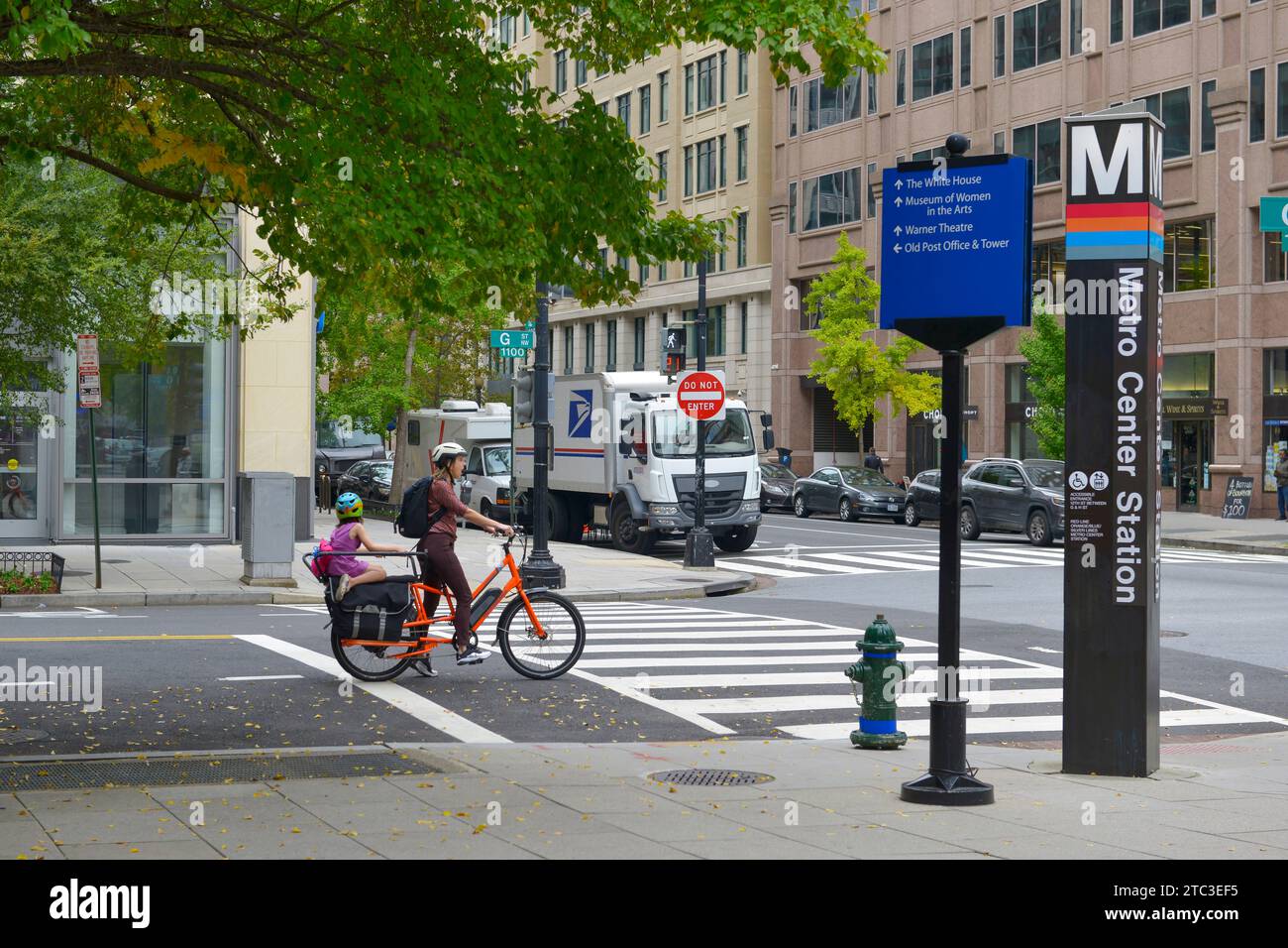 Donna con un bambino in bicicletta all'incrocio tra la G e la 12th St NW a Washington DC Foto Stock