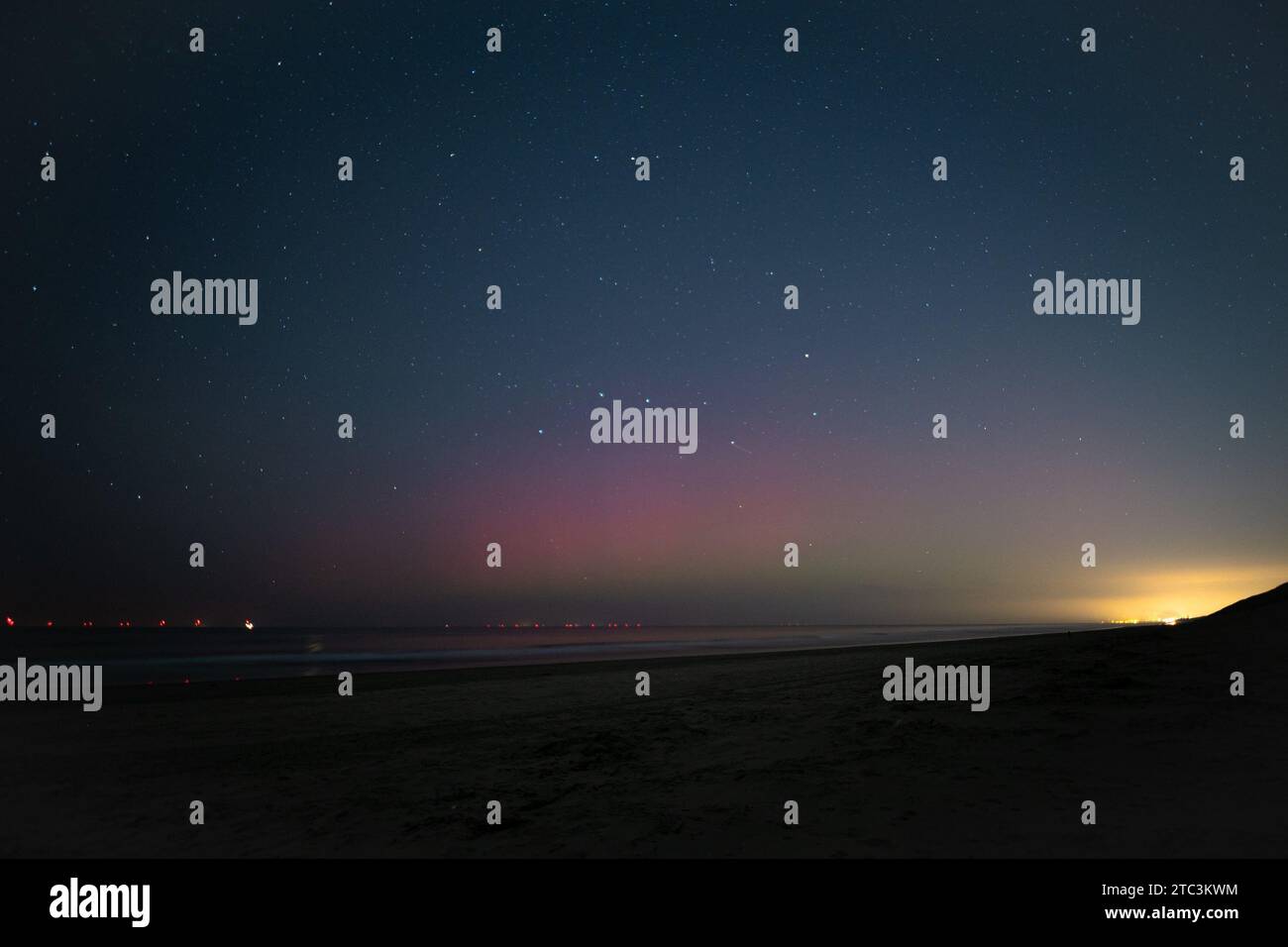 L'aurora boreale di colore viola o l'aurora boreale sotto un cielo stellato sulla spiaggia del Mare del Nord. Foto Stock
