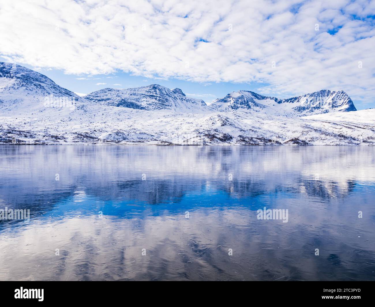 Montagna innevata che si riflette in un tranquillo lago ghiacciato in Norvegia Foto Stock