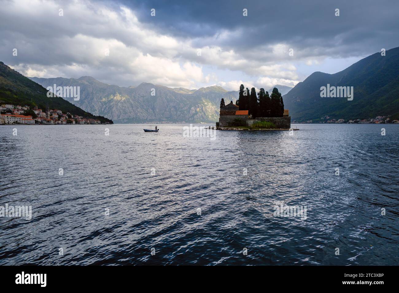 Un uomo che pesca da una barca vicino all'isola di San Giorgio (Sveti Dorde) nella baia di Cattaro, vicino a Perast, Montenegro. Questa è una vista dall'altro isolotto Foto Stock