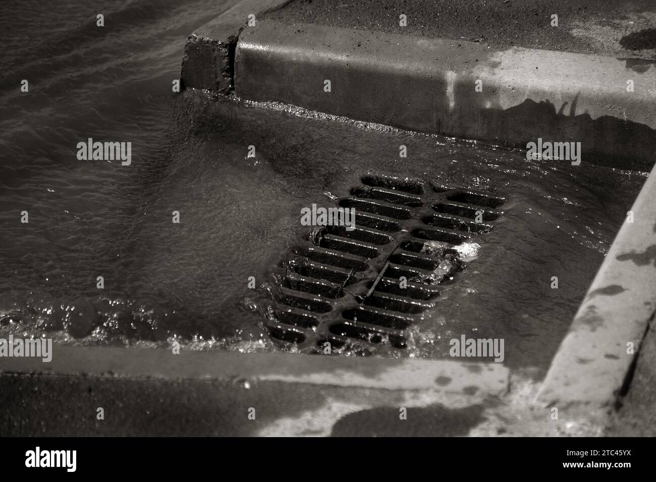 Flusso d'acqua durante la pioggia intensa e intasamento delle acque reflue stradali. Il flusso d'acqua durante un forte uragano nelle fognature. Sistema di tempeste fognarie Foto Stock