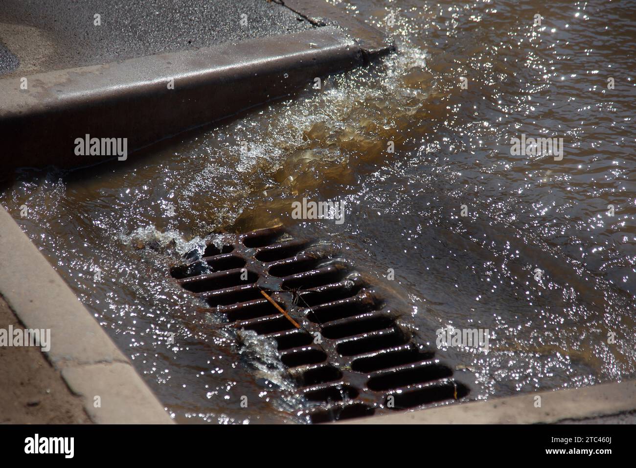Flusso d'acqua durante la pioggia intensa e intasamento delle acque reflue stradali. Il flusso d'acqua durante un forte uragano nelle fognature. Sistema di tempeste fognarie Foto Stock