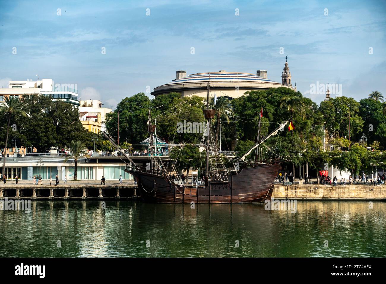 Una replica dettagliata di un vecchio veliero ormeggiato lungo il fiume a Siviglia, in Spagna, con paesaggio urbano sullo sfondo. Foto Stock