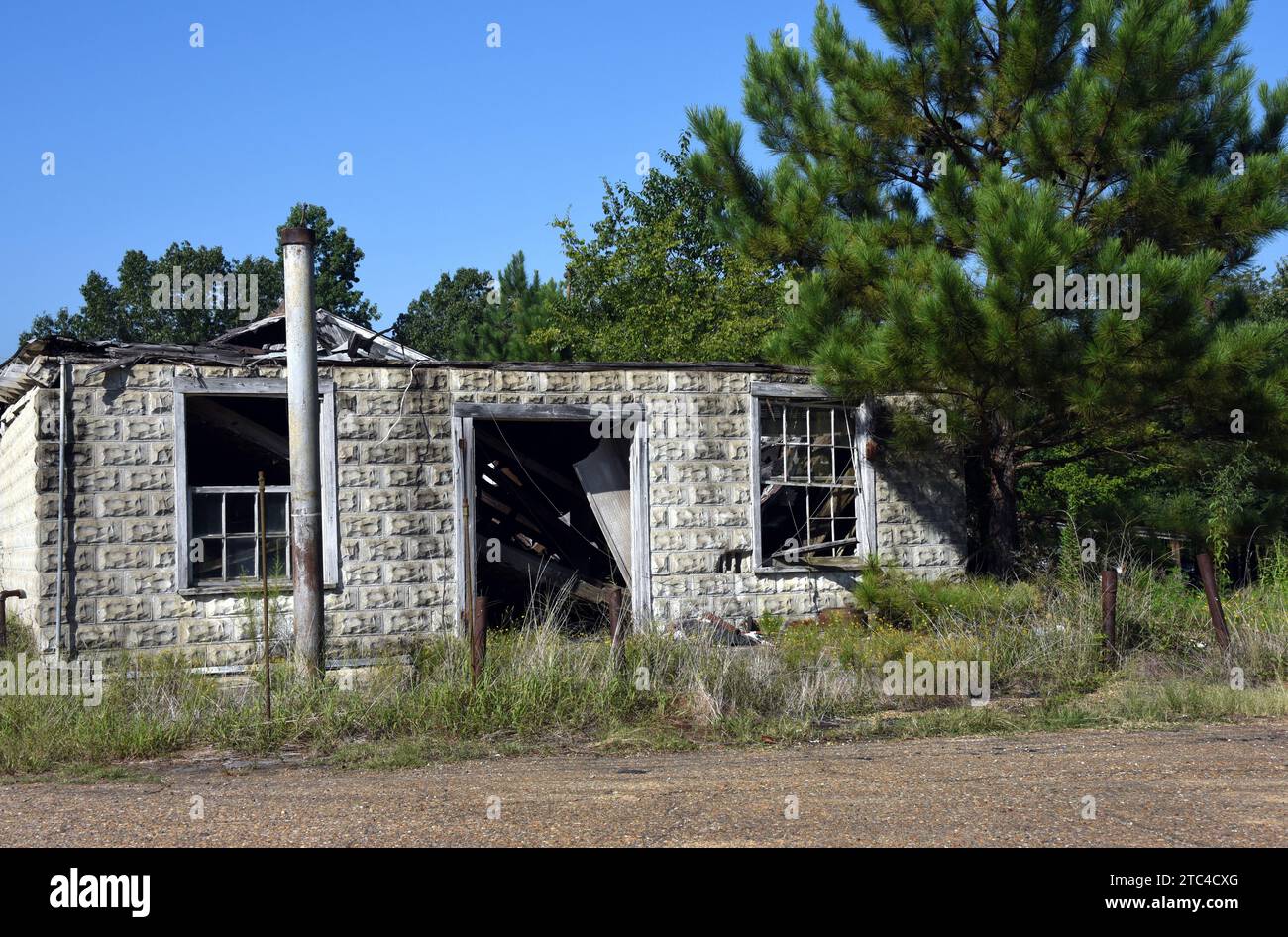 Il vecchio negozio di campagna è derelict e siede in rovina. Il palo di metallo di segno sta davanti al deposito dove la pompa del gas ha seduto. Il tetto è stato scavato. Foto Stock