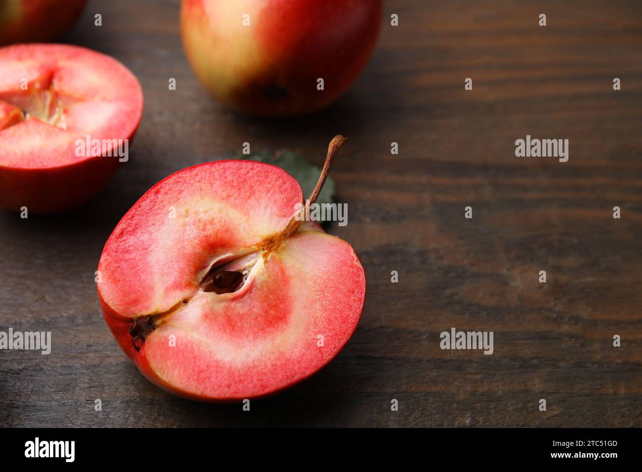 Mele gustose con polpa rossa su tavola di legno, primo piano. Spazio per il testo Foto Stock