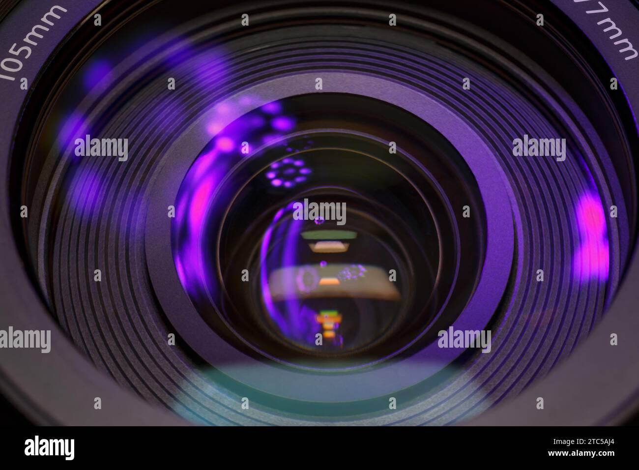 Riflessi violetti nel vetro di una lente fotografica. Fotografia macro in tonalità scure Foto Stock