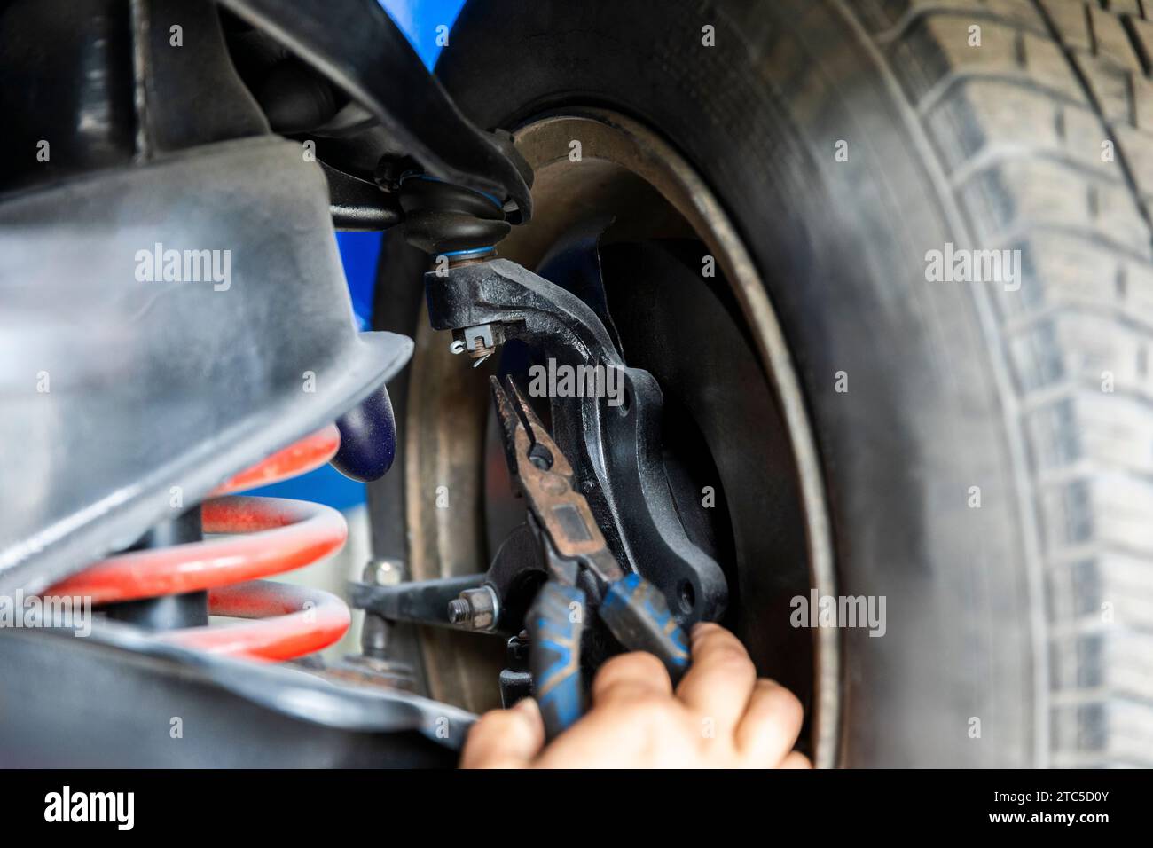 Meccanico che cerca un perno con pinze, affronta un'attività di manutenzione che coinvolge componenti complessi. Foto Stock