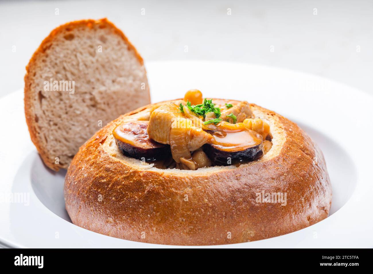 stufato con carne di maiale, ceci e sausge in pane Foto Stock