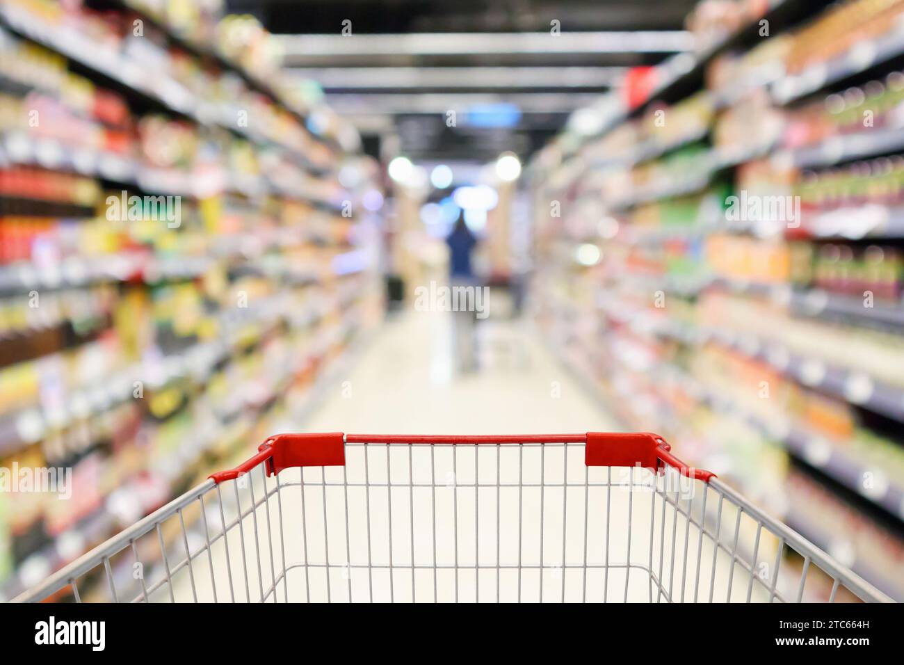 scaffali del supermercato corridoio con carrello della spesa vuoto sfocatura interna sfocata, sfondo chiaro bokeh Foto Stock