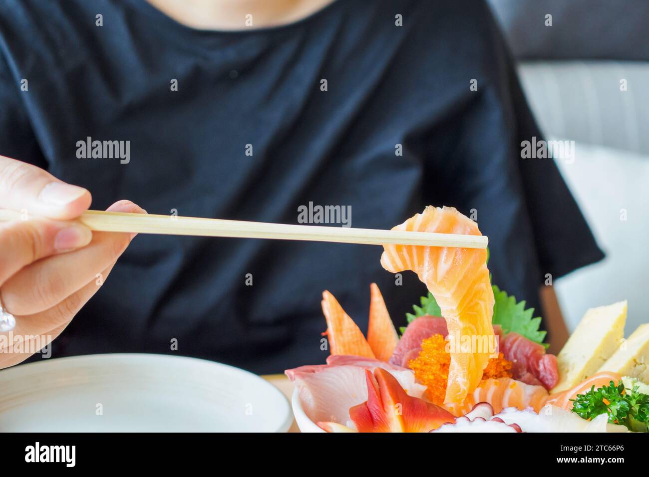 Fetta di salmone in bacchette, mangiare Sashimi Rice Bowl Chirashi Don cibo giapponese Foto Stock
