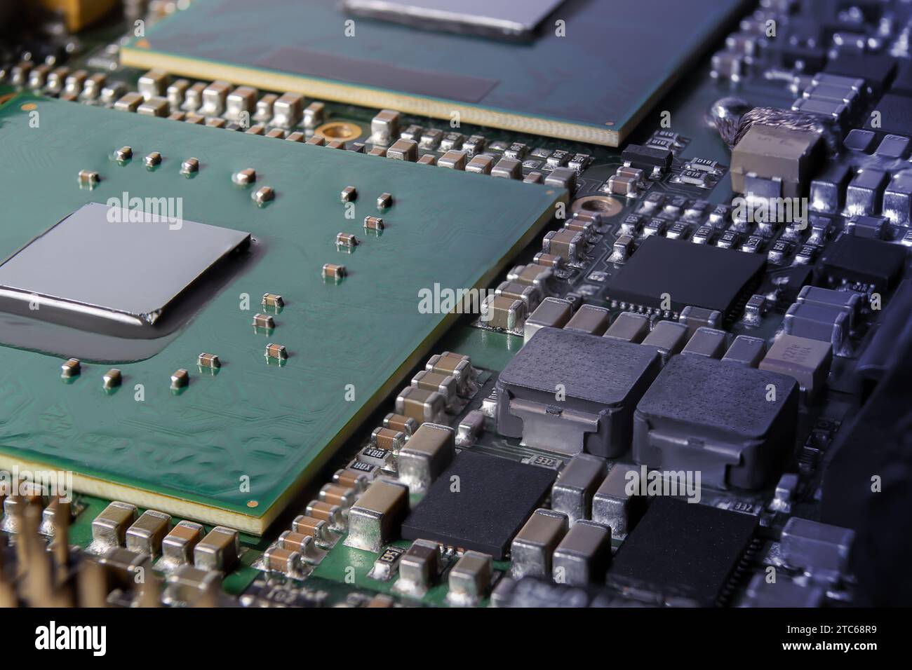 Primo piano sulla moderna scheda elettronica con processore, circuiti integrati e componenti passivi a montaggio superficiale. Background tecnologico Foto Stock