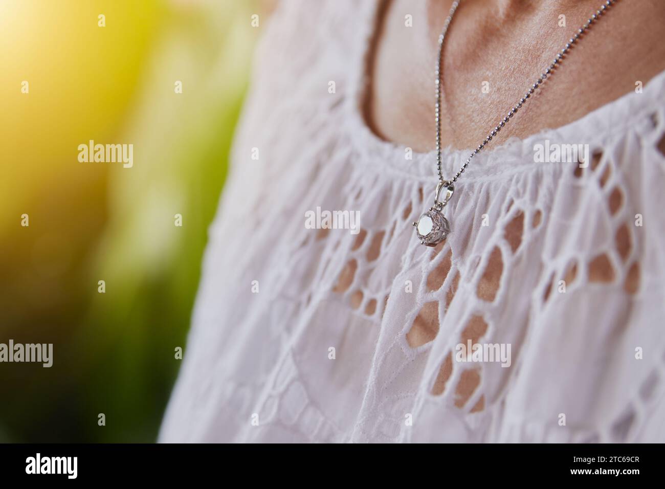 Donna che indossa una collana con diamanti argento e una camicia in pizzo su sfondo verde giardino e luce solare. Amore, Ramance, concetto di coppia e relazione in Good CE Foto Stock