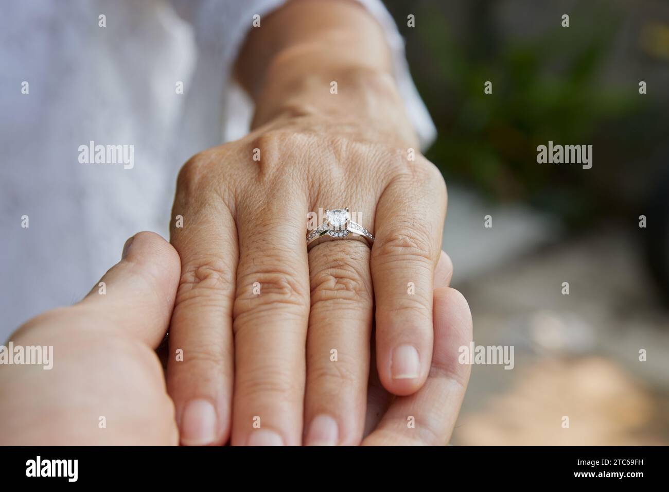 La mano dell'uomo che tiene la mano della donna e l'anello per matrimoni diamanti. Amante o coppia che si tiene per mano scena Concept in cerimonia Foto Stock