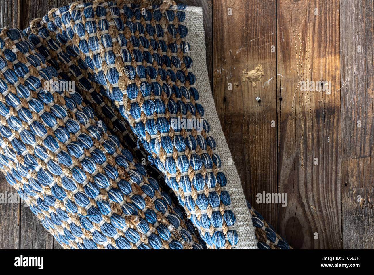 Tappeto in denim geometrico intrecciato a mano su pavimento in legno. Foto Stock