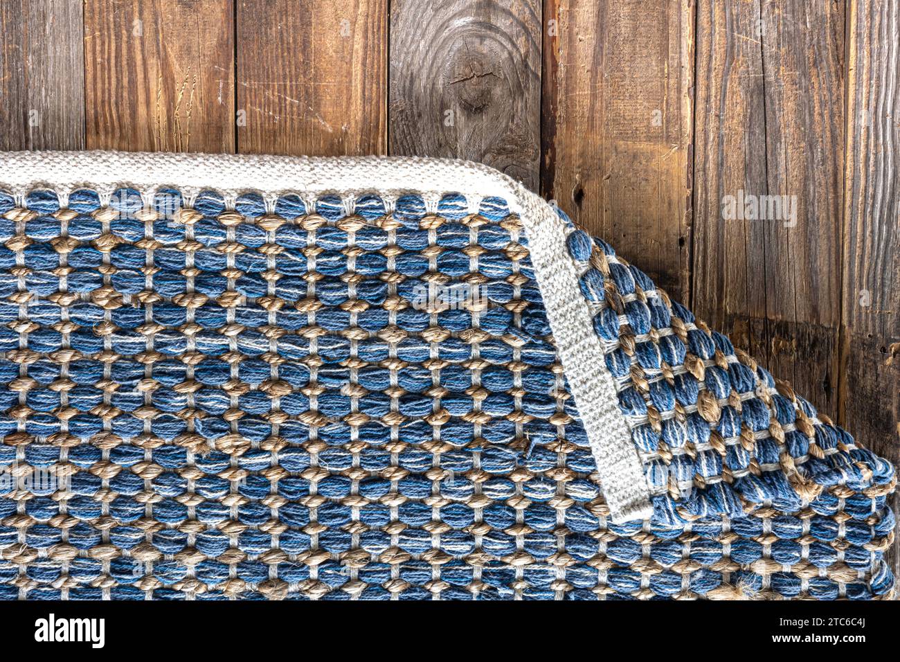 Tappeto in denim geometrico intrecciato a mano su pavimento in legno. Foto Stock