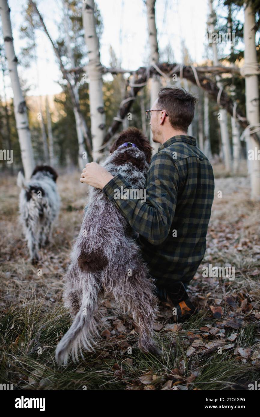 Un uomo e un cane Griffon in piedi insieme nel bosco dell'Idaho Foto Stock