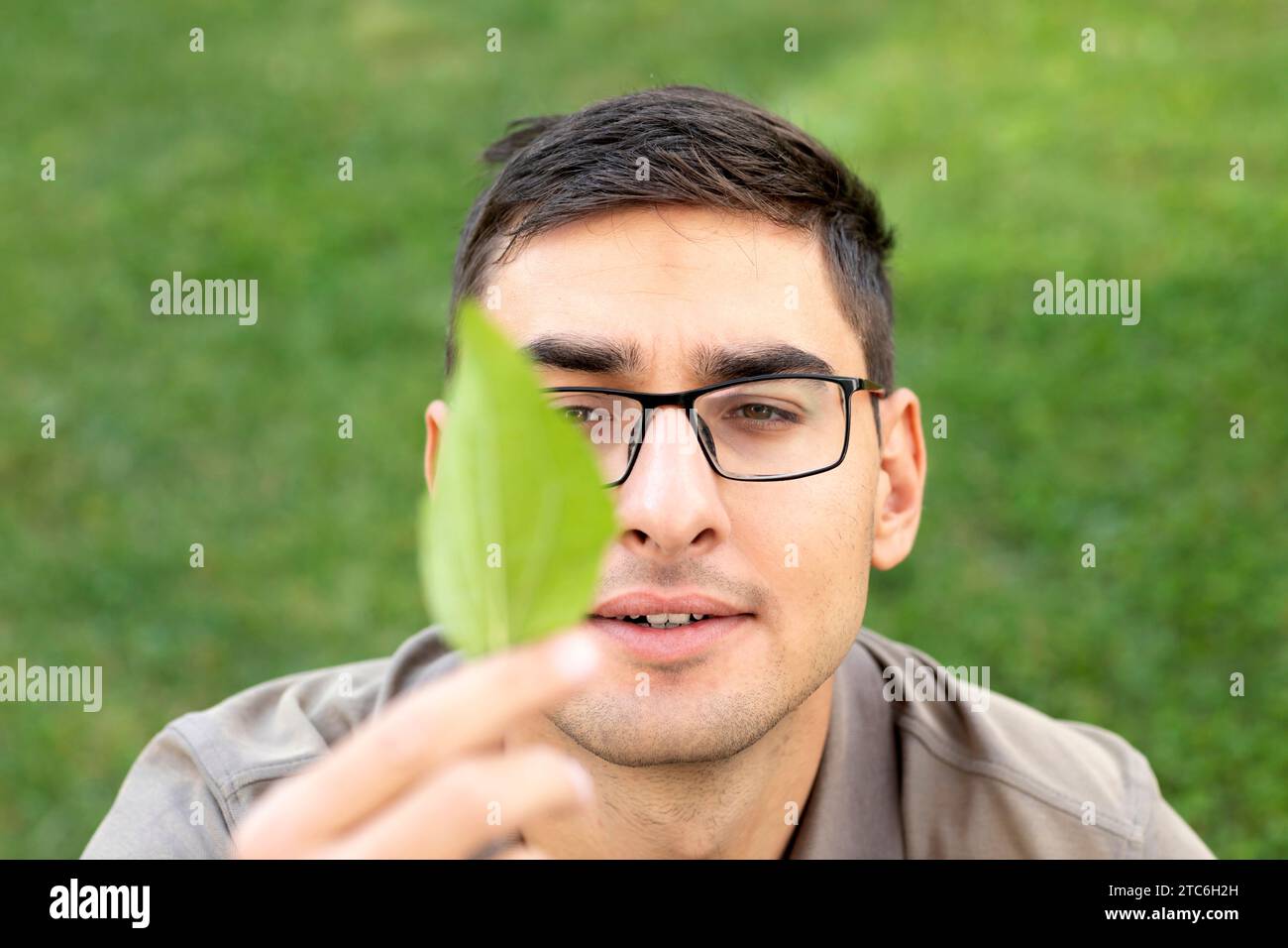 un giovane che guarda la foglia verde in mano Foto Stock