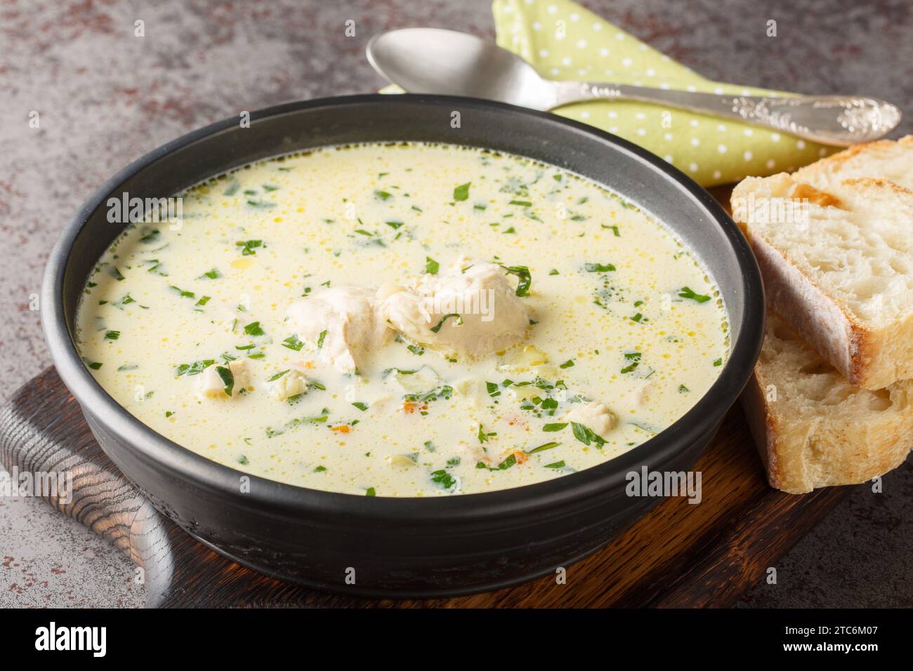 Zuppa rumena di pollo acida Ciorba Radauteana con verdure e panna acida primo piano sul piatto sul tavolo. Orizzontale Foto Stock