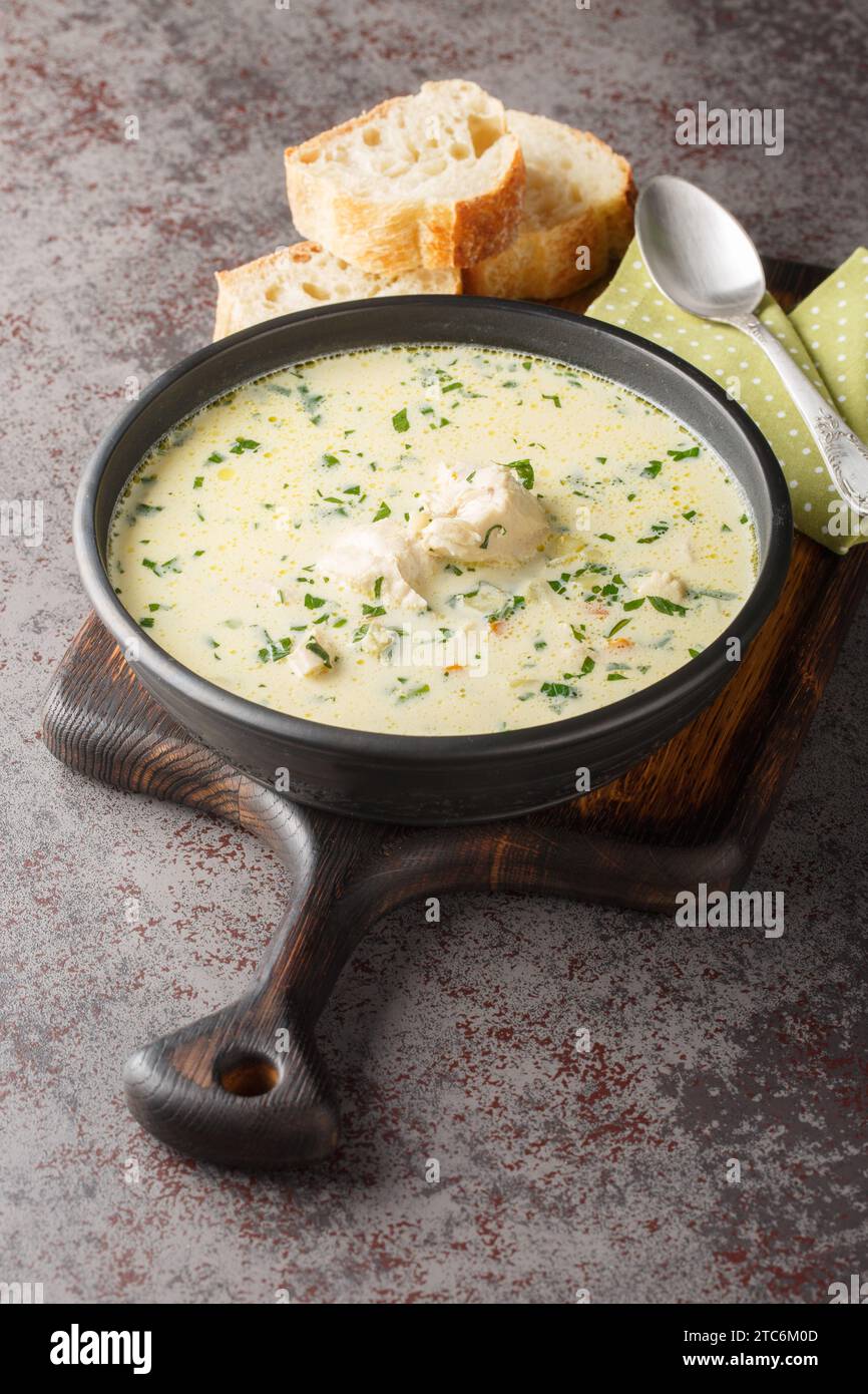 Zuppa di pollo rumena di nome Ciorba Radauteana primo piano sul piatto sul tavolo. Verticale Foto Stock