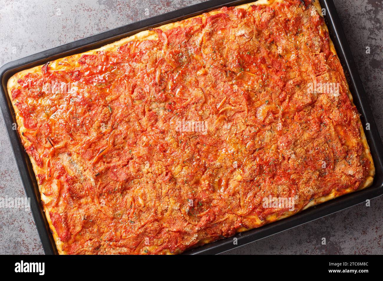 La pizza siciliana più famosa di Sfincione è una focaccia spessa condita con salsa di pomodoro, acciughe e primo piano di formaggio sulla teglia da forno sul tavolo. Ho Foto Stock