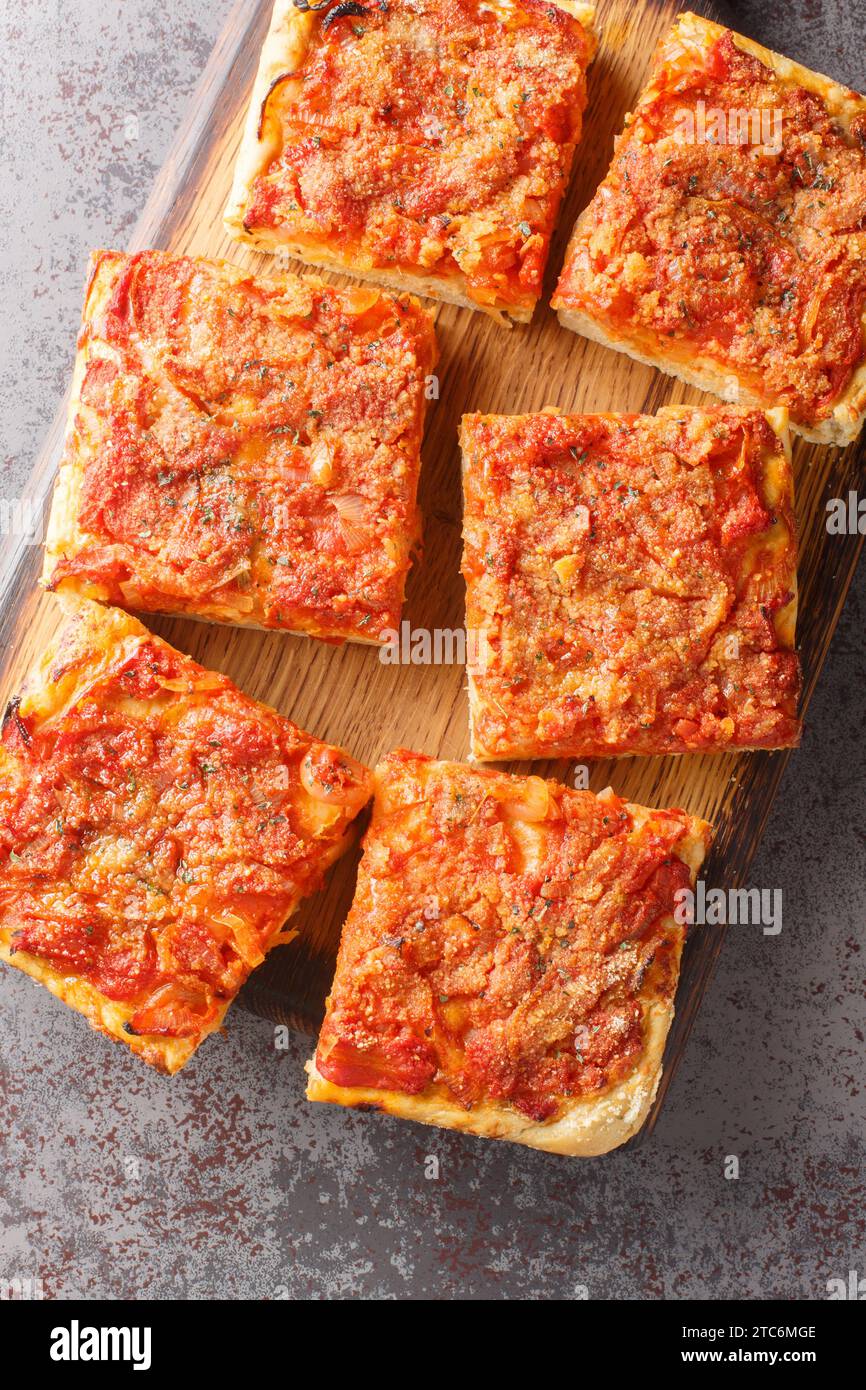 Focaccia italiana siciliana Sfincione con pomodoro, cipolla, acciughe, formaggio, origano e pangrattato primo piano sulla tavola di legno sul tavolo. Verticale Foto Stock Focaccia italiana siciliana Sfincione con pomodoro, cipolla, acciughe, formaggio, origano e pangrattato primo piano sulla tavola di legno sul tavolo. Verticale Foto Stock