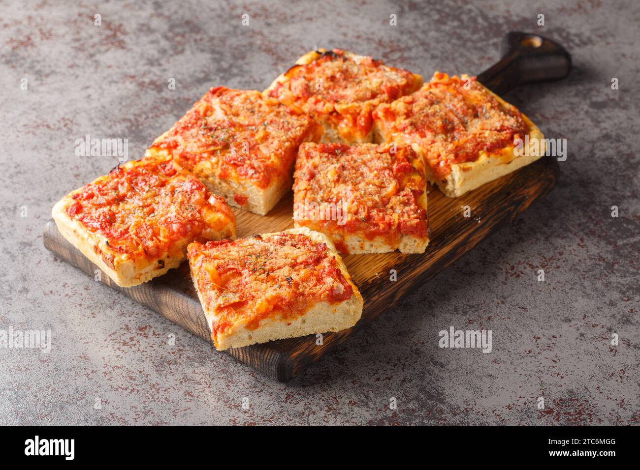 Sfincione tipica focaccia al forno molto morbida e condita con pomodoro, cipolla, acciughe, formaggio, origano e pangrattato primo piano sul boa di legno Foto Stock