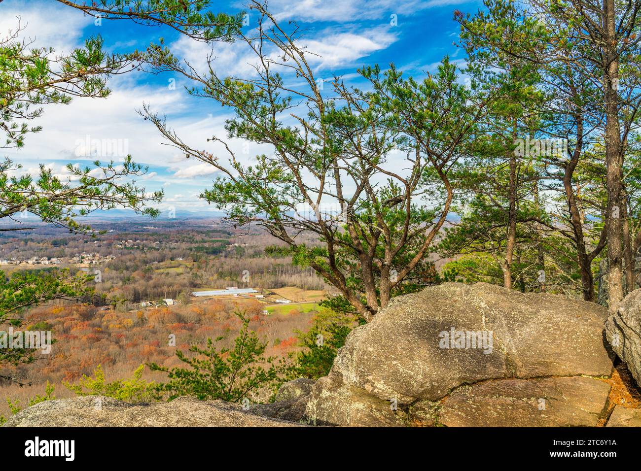 Una vista panoramica della cima di una collina da un punto di osservazione della scogliera, caratterizzata da una lussureggiante vegetazione verde e da un cielo blu cristallino Foto Stock
