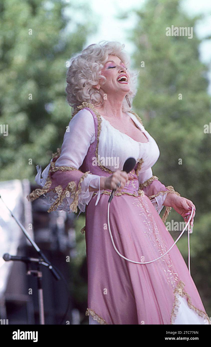 La superstar Dolly Parton si esibisce sul palco di un concerto durante il suo tour del Midwest del 1978, la testa è inclinata all'indietro e sta facendo una bella risata. Foto Stock