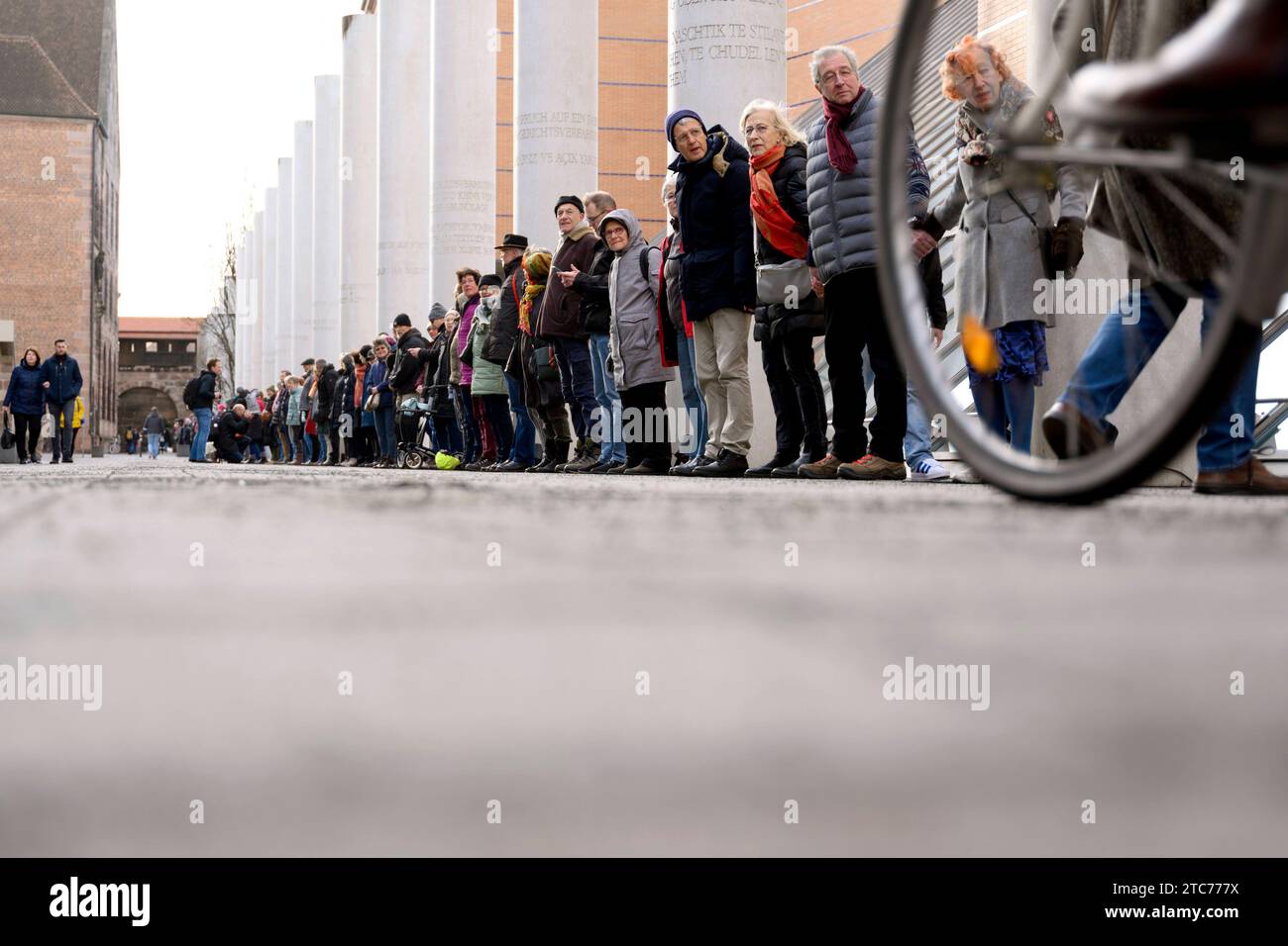 ALS Aktion zum 75. Jahrestag der Verkündung der Allgemeinen Erklärung der Menschenrechte bilden Teilnehmer eine Menschenkette in der Straße der Menschenrechte. Auf den Säulen in der Straße sind die 30 Artikel der un-Menschenrechtscharta in verschiedenen Sprachen zu lesen. Nürnberg, 10.12.2023 Bayern Deutschland *** come azione per celebrare il 75° anniversario della proclamazione della dichiarazione universale dei diritti dell'uomo, i partecipanti formano una catena umana nella strada dei diritti umani i 30 articoli della carta dei diritti umani delle Nazioni Unite possono essere letti in varie lingue sui pilastri della strada N Foto Stock