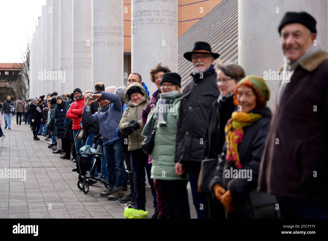 ALS Aktion zum 75. Jahrestag der Verkündung der Allgemeinen Erklärung der Menschenrechte bilden Teilnehmer eine Menschenkette in der Straße der Menschenrechte. Auf den Säulen in der Straße sind die 30 Artikel der un-Menschenrechtscharta in verschiedenen Sprachen zu lesen. Nürnberg, 10.12.2023 Bayern Deutschland *** come azione per celebrare il 75° anniversario della proclamazione della dichiarazione universale dei diritti dell'uomo, i partecipanti formano una catena umana nella strada dei diritti umani i 30 articoli della carta dei diritti umani delle Nazioni Unite possono essere letti in varie lingue sui pilastri della strada N Foto Stock