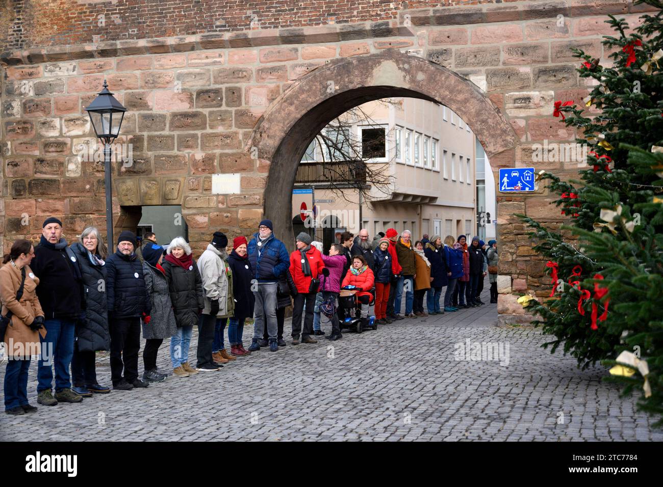 ALS Aktion zum 75. Jahrestag der Verkündung der Allgemeinen Erklärung der Menschenrechte bilden Teilnehmer eine Menschenkette in der Straße der Menschenrechte. Auf den Säulen in der Straße sind die 30 Artikel der un-Menschenrechtscharta in verschiedenen Sprachen zu lesen. Nürnberg, 10.12.2023 Bayern Deutschland *** come azione per celebrare il 75° anniversario della proclamazione della dichiarazione universale dei diritti dell'uomo, i partecipanti formano una catena umana nella strada dei diritti umani i 30 articoli della carta dei diritti umani delle Nazioni Unite possono essere letti in varie lingue sui pilastri della strada N Foto Stock