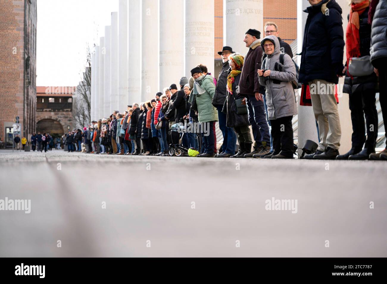 ALS Aktion zum 75. Jahrestag der Verkündung der Allgemeinen Erklärung der Menschenrechte bilden Teilnehmer eine Menschenkette in der Straße der Menschenrechte. Auf den Säulen in der Straße sind die 30 Artikel der un-Menschenrechtscharta in verschiedenen Sprachen zu lesen. Nürnberg, 10.12.2023 Bayern Deutschland *** come azione per celebrare il 75° anniversario della proclamazione della dichiarazione universale dei diritti dell'uomo, i partecipanti formano una catena umana nella strada dei diritti umani i 30 articoli della carta dei diritti umani delle Nazioni Unite possono essere letti in varie lingue sui pilastri della strada N Foto Stock