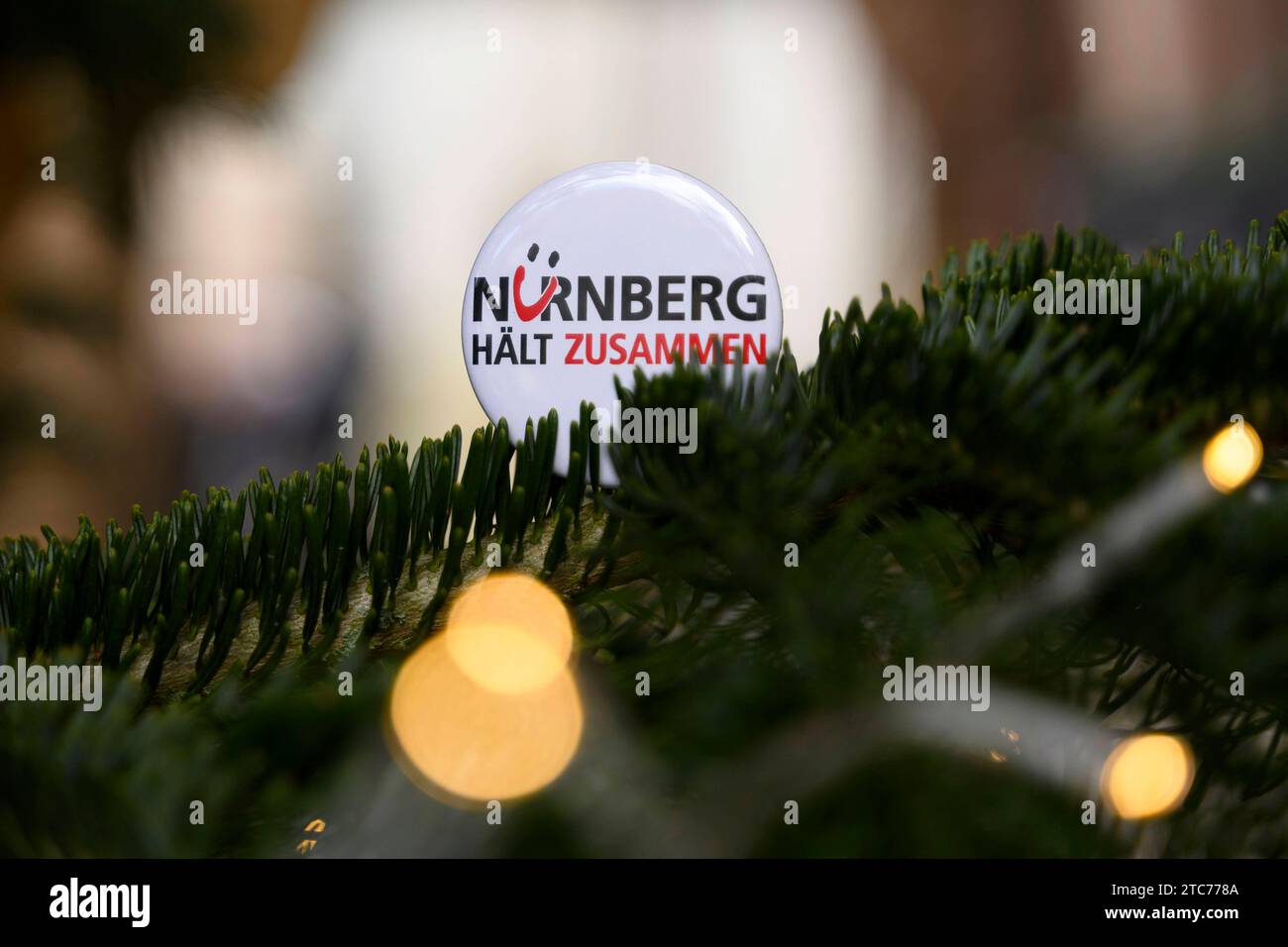 Ein button mit der Aufschrift Nürnberg hält zusammen , ein motto, unter dem ein Bündnis gesellschaftlicher Gruppen seit 2015 fr ein buntes und tolerantes Nürnberg wirbt. ALS Aktion zum 75. Jahrestag der Verkündung der Allgemeinen Erklärung der Menschenrechte bilden Teilnehmer eine Menschenkette in der Straße der Menschenrechte. Auf den Säulen in der Straße sind die 30 Artikel der un-Menschenrechtscharta in verschiedenen Sprachen zu lesen. Nürnberg, 10.12.2023 Bayern Deutschland *** Un bottone con l'iscrizione Norimberga si attacca insieme, un motto sotto il quale un'alleanza di gruppi sociali ha ape Foto Stock