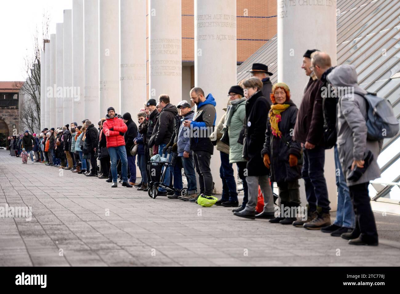 ALS Aktion zum 75. Jahrestag der Verkündung der Allgemeinen Erklärung der Menschenrechte bilden Teilnehmer eine Menschenkette in der Straße der Menschenrechte. Auf den Säulen in der Straße sind die 30 Artikel der un-Menschenrechtscharta in verschiedenen Sprachen zu lesen. Nürnberg, 10.12.2023 Bayern Deutschland *** come azione per celebrare il 75° anniversario della proclamazione della dichiarazione universale dei diritti dell'uomo, i partecipanti formano una catena umana nella strada dei diritti umani i 30 articoli della carta dei diritti umani delle Nazioni Unite possono essere letti in varie lingue sui pilastri della strada N Foto Stock