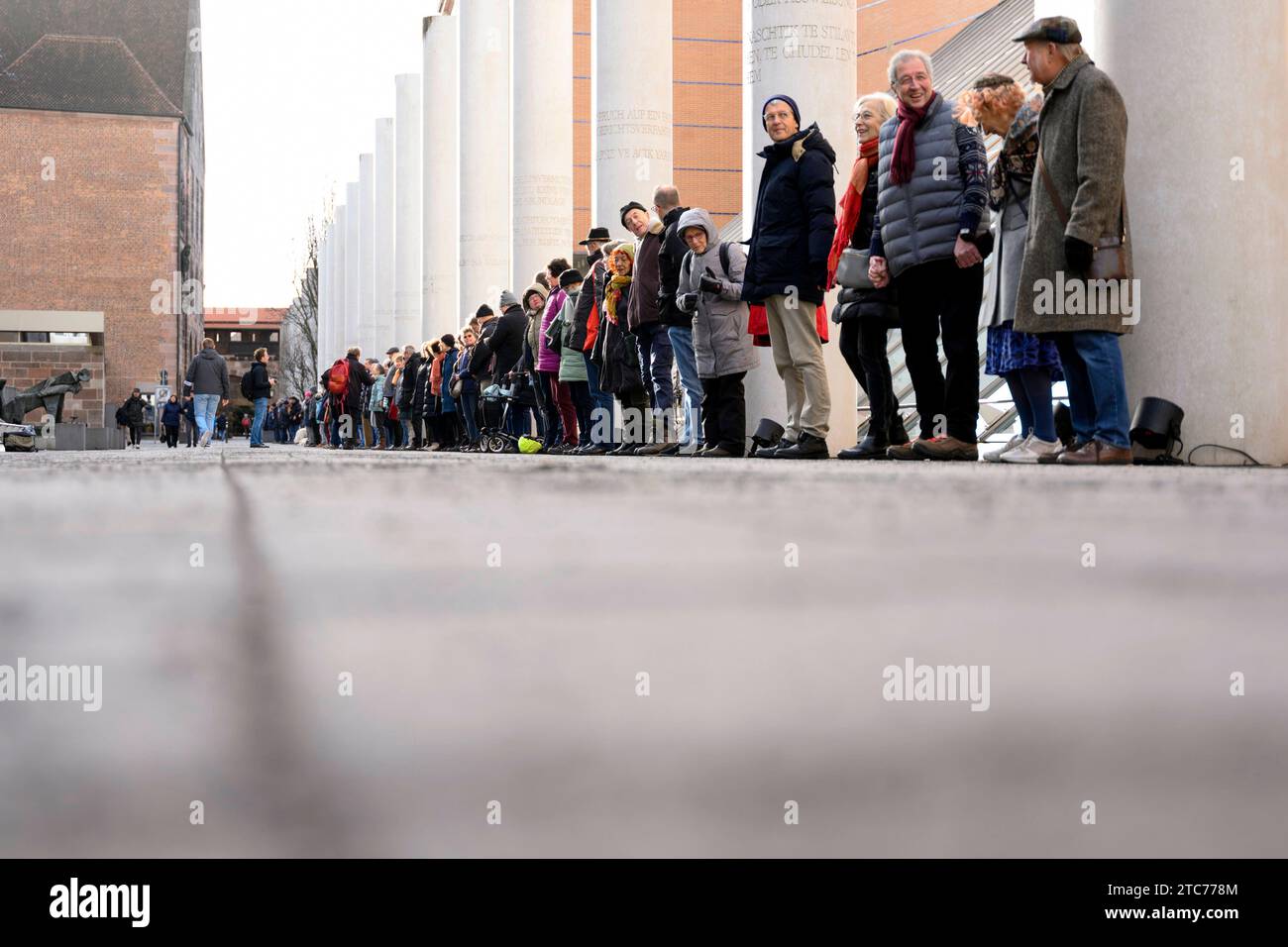 ALS Aktion zum 75. Jahrestag der Verkündung der Allgemeinen Erklärung der Menschenrechte bilden Teilnehmer eine Menschenkette in der Straße der Menschenrechte. Auf den Säulen in der Straße sind die 30 Artikel der un-Menschenrechtscharta in verschiedenen Sprachen zu lesen. Nürnberg, 10.12.2023 Bayern Deutschland *** come azione per celebrare il 75° anniversario della proclamazione della dichiarazione universale dei diritti dell'uomo, i partecipanti formano una catena umana nella strada dei diritti umani i 30 articoli della carta dei diritti umani delle Nazioni Unite possono essere letti in varie lingue sui pilastri della strada N Foto Stock
