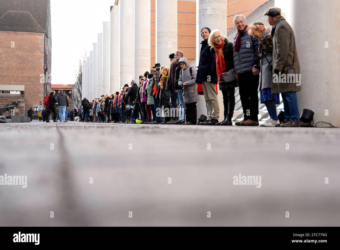 ALS Aktion zum 75. Jahrestag der Verkündung der Allgemeinen Erklärung der Menschenrechte bilden Teilnehmer eine Menschenkette in der Straße der Menschenrechte. Auf den Säulen in der Straße sind die 30 Artikel der un-Menschenrechtscharta in verschiedenen Sprachen zu lesen. Nürnberg, 10.12.2023 Bayern Deutschland *** come azione per celebrare il 75° anniversario della proclamazione della dichiarazione universale dei diritti dell'uomo, i partecipanti formano una catena umana nella strada dei diritti umani i 30 articoli della carta dei diritti umani delle Nazioni Unite possono essere letti in varie lingue sui pilastri della strada N Foto Stock